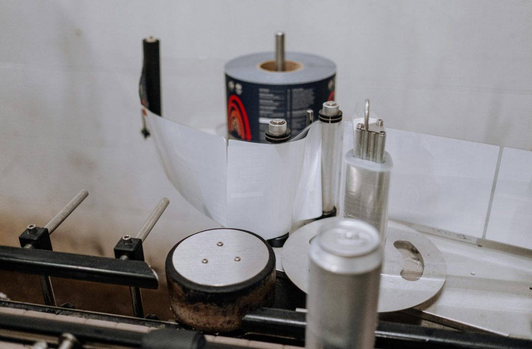 Detailed view of a brewery machinery used for labeling beer cans in an industrial setting.