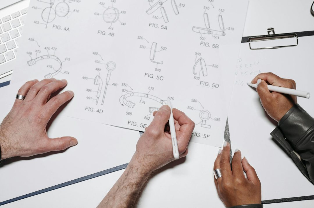 Two people collaborating over technical drawings in a well-lit workspace.